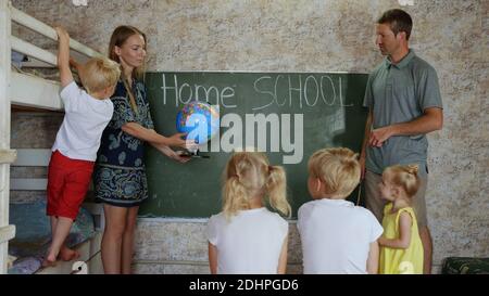 Home School-Konzept. Eltern lehren ihre Kinder mit einem Globus in der Hand. Stockfoto