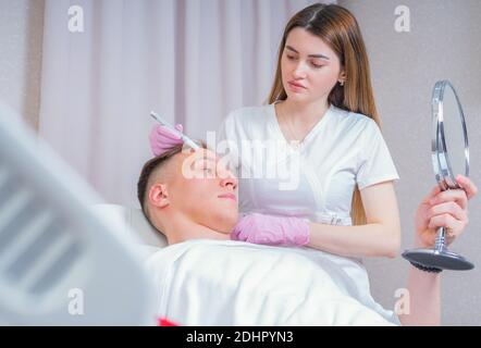 Männliche Kosmetik. Ein gut aussehender Mann, der im luxuriösen Spa eine Gesichtsbehandlung bekommt Stockfoto