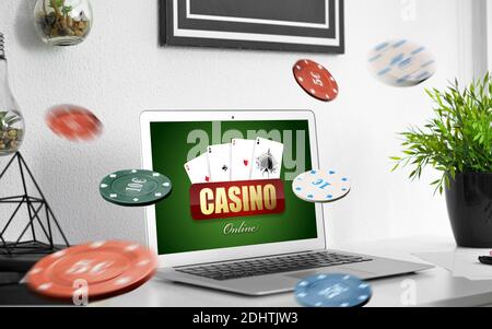 Text CASINO ONLINE auf dem Bildschirm des Laptops auf dem Tisch in Zimmer Stockfoto