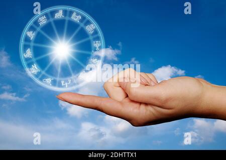 Weibliche Hand mit Finger, der ein astrologisches Rad hält Stockfoto