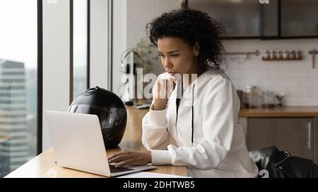 Pensive biracial weiblich arbeiten auf Laptop am Schreibtisch Stockfoto