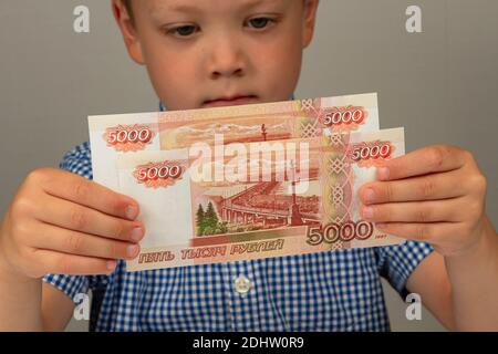 Das Kind erhielt Geld vom Staat während des Coronavirus Und hält sie in seinen Händen Stockfoto