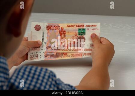 Das Kind erhielt Geld vom Staat während des Coronavirus Und hält sie in seinen Händen Stockfoto