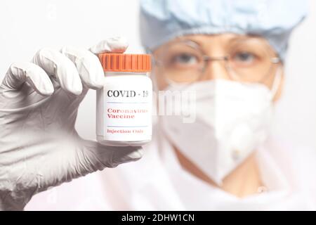 Ärztin hält eine Flasche Impfstoff covid-19. Wissenschaftler in steriler Kleidung macht einen Impfstoff covid-19. Stockfoto