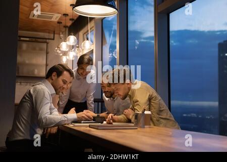Lächelnde Kollegen treffen sich spät im Büro Stockfoto