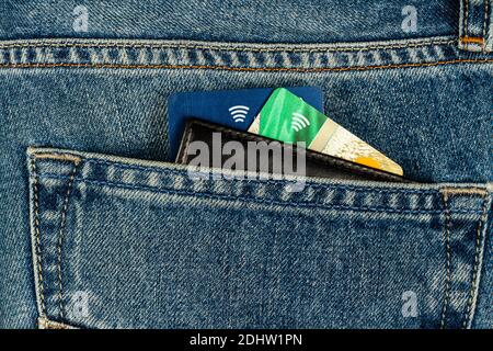 Schwarze Brieftasche und Bankkarten ragen aus blauen Jeans Tasche Stockfoto