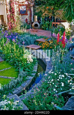 Bunt gut bepflanzten Garten mit Terrasse und Rill in einem Stadtgarten Stockfoto