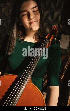 Teenager-Mädchen mit Cello, posiert in einem Flur. Stockfoto