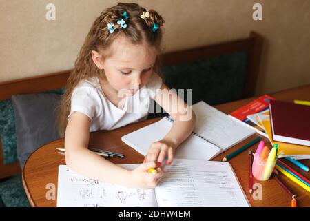 Hübsches kleines Mädchen macht Hausaufgaben zu Hause. Ausbildung zu Hause Stockfoto