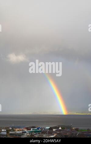 Heller Regenbogen hoch im Himmel über dem Meer im Dunkeln Sturm Stockfoto