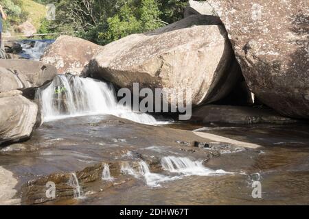 Ein schöner Wasserfall in einem Bergbach mit umschlingenden Felsen Und atemberaubende Felsformationen und Muster Stockfoto