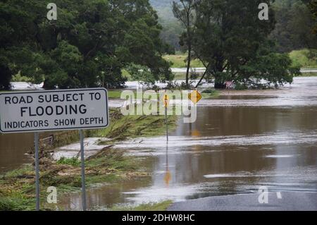 Überflutete Straßen und Ackerland, wo der Fluss Coomera seine Ufer geplatzt hat. Warnschild neben blockierter Straße. Queensland, Australien. Stockfoto