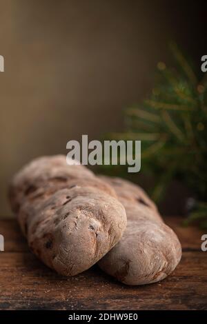 Vörtbröd Roggenbrot mit Rosinen auf einem Holztisch. Mit pinaceae Zweigen im Hintergrund. Schwedisches traditionelles weihnachtsbrot Würze Brot oder Würze lo Stockfoto