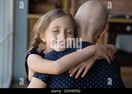 Nahaufnahme lächelnde kleine Tochter umarmt kranke haarlose Mutter Stockfoto