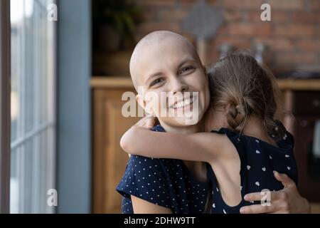Kopf erschossen Porträt lächelnd kranke Mutter umarmt kleine Tochter Stockfoto