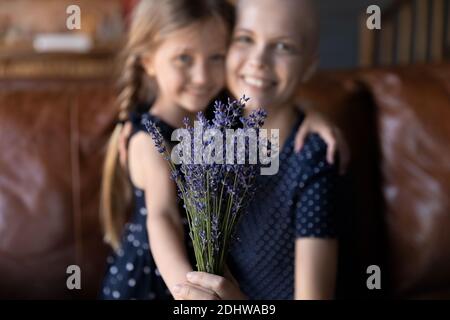 Nahaufnahme kleine Tochter präsentiert Blumen zu kranken Mutter Stockfoto