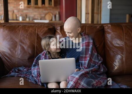 Glückliche kranke Mutter Krebs-Patientin und kleine Tochter mit Laptop Stockfoto