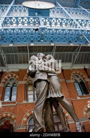 Paul Days Skulptur der Umarmung des Paares „The Meeting Place“ am Bahnhof St. Pancras in London unter der Uhr, wo sich Generationen von Paaren getrennt haben Stockfoto