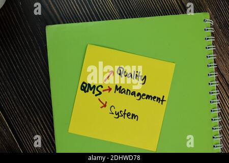 QMS - Qualitätsmanagementsystem Schreiben Sie auf Haftnotizen isoliert auf Holztisch. Stockfoto