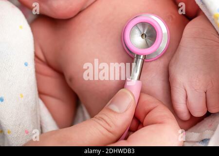 Eine Krankenschwester, die ein Stethoskop verwendet, um das eines Neugeborenen zu untersuchen Herz Stockfoto