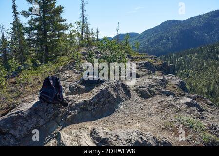 Zwei Wanderrucksäcke befinden sich auf einem kleinen, felsigen Plateau am Ende des Liberty Falls Trail, über Bergen mit dichten Wäldern. Stockfoto