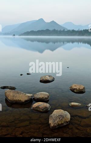 Felsen liegen in den stillen Gewässern von Derwent Wasser mit Catbells reflektieren. Stockfoto