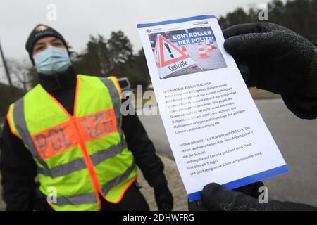 Ahlbeck, Deutschland. Dezember 2020. Vor dem Grenzübergang Ahlbeck hält ein Polizist der Staatspolizei einen Hinweis auf die Quarantäneregeln in Mecklenburg-Vorpommern in der Hand. Um Coronainfektionen einzudämmen, überprüft die Staatspolizei in Mecklenburg-Vorpommern nun auch Reisende an der Grenze zu Polen. Quelle: Stefan Sauer/dpa/Alamy Live News Stockfoto