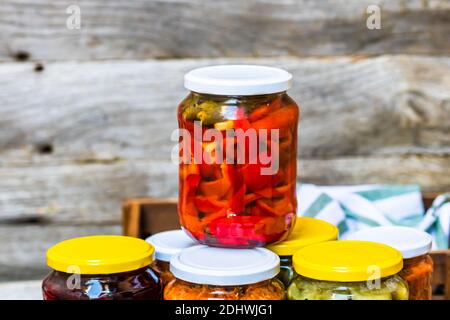 Gläser mit verschiedenen Dosen Gemüse und Obst, Gläser mit zacusca. Konserviertes Lebensmittelkonzept in rustikaler Zusammensetzung. Stockfoto