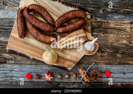 Blick von der Tischplatte mit hausgemachten Speck und Würstchen und Weihnachtliche Einrichtung auf rustikalem Holzhintergrund Stockfoto