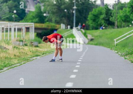 Schöner junger Mann, der sich vor dem morgendlichen Training im Park dehnt und sich aufwärmt Stockfoto