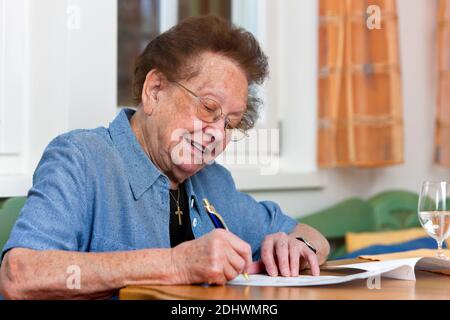 Eine alte Frau schreibt einen Vertrag, Senioren, Stockfoto