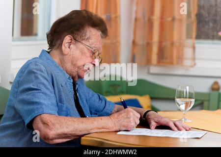 Eine alte Frau schreibt einen Vertrag, Senioren, Stockfoto