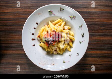 Einstellung von Pasta Carbonara mit Penne Pasta in weiß gemacht Teller auf Holztisch Stockfoto