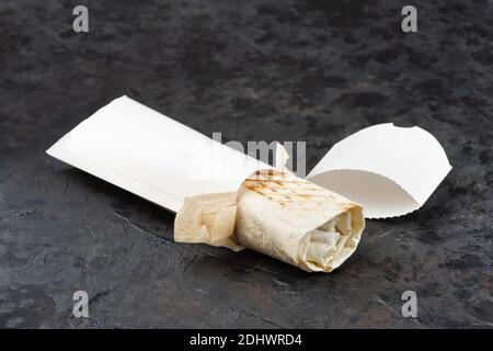 Traditionelles orientalisches Shawarma aus umweltfreundlicher Pappe. Oberfläche aus dunklem Stein. Konzept von Öko-Verpackungen von Wertstoffen. Speicherplatz kopieren Stockfoto