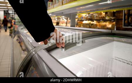 Mann Hand öffnen eine transparente Kühlschranktür in einem Supermarkt Stockfoto