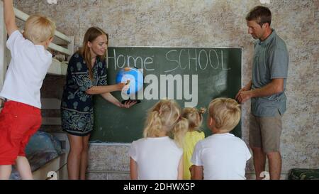 Home School-Konzept. Eltern lehren ihre Kinder mit einem Globus in der Hand. Stockfoto