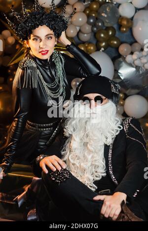 Emotionale Nahaufnahme Portrait DJ Santa Claus mit Sonnenbrillen und Kopfhörer Hören zu Weihnachten Musik und Snow Maiden Schwarz Lederjacke Spaß haben. Rockparty Time. Stockfoto