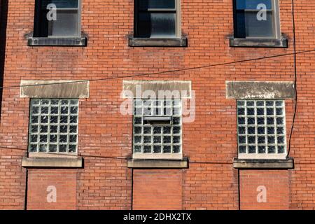 Rotes Ziegelsteingebäude, altes gewerbliches Industriegebäude, untere Fenster mit Glasziegel, architektonische Details, horizontale Aspec Stockfoto