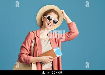 Porträt von jungen glücklichen Touristen in Sonnenbrillen und mit Flugzeug Tickets lächeln auf Kamera isoliert auf blauem Hintergrund Stockfoto