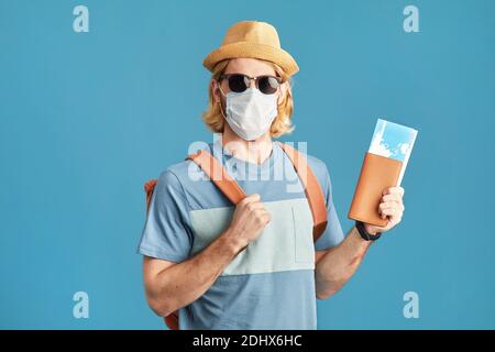 Portrait des jungen Mannes in Sonnenbrille und in Maskenhaltung Tickets, die während einer Pandemie reisen Stockfoto