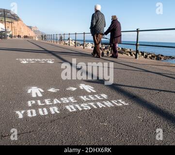 Halten Sie Ihre Distanzschilder, soziale Distanzierung, gemalt auf der Esplanade in Sidmouth, Devon, England, Großbritannien Stockfoto