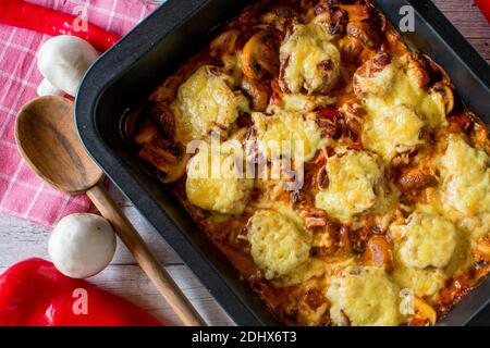 Schweinelende Gratin mit köstlicher Pilzgemüsesauce und gekrönt Mit geriebenem gouda-Käse Stockfoto