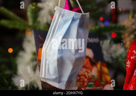 Viersen, Deutschland - 9. Dezember. 2020: Nahaufnahme der chirurgischen Gesichtsschutz Maske in weihnachtstanne mit verschwommenem Wham letzten weihnachtslied Vinyl Recor Stockfoto