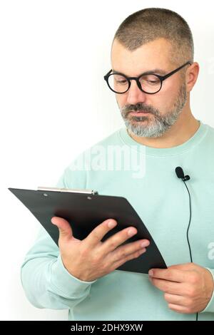 Porträt von bärtigen Geschäftsmann Trainer trägt Brille mit Mikrofon und Zwischenablage. Mentor Referent hält Online-Lektion Stockfoto