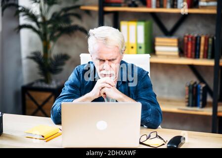 Older man is using laptop for working indoor Stockfoto