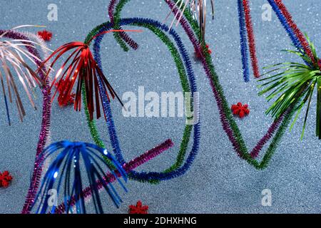 2021 Neujahrskarte mit funkelnden bunten Zahlen von Pfeifenreinigern oder Pfeifenwaschmaschine, glitzerndem türkisfarbenem Hintergrund mit roten festlichen Sternen. Stockfoto