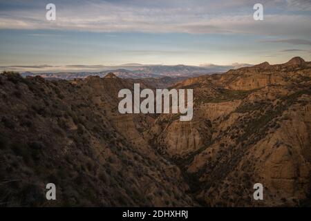 Aride Badlands Landschaft mit kleinen Büschen und Wolken in der Himmel Stockfoto