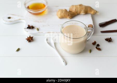 Heißer Masala-Tee in einer Glasschale mit Zutaten auf einem weißen Teller. Indisches Essen. Horizontale Ausrichtung. Speicherplatz kopieren. Stockfoto