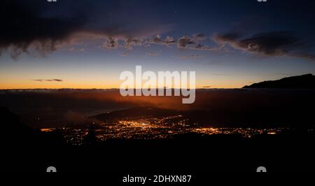 Stadt beleuchtet in der Nacht vom Berg aus gesehen mit Wolken Und Sterne am Himmel Stockfoto