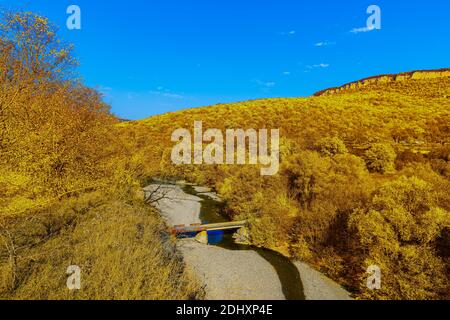 Berglandschaft mit einem kleinen Gebirgsfluss mit einer Brücke darüber in einer tiefen Schlucht in der Republik Adygea in Russland. Stockfoto